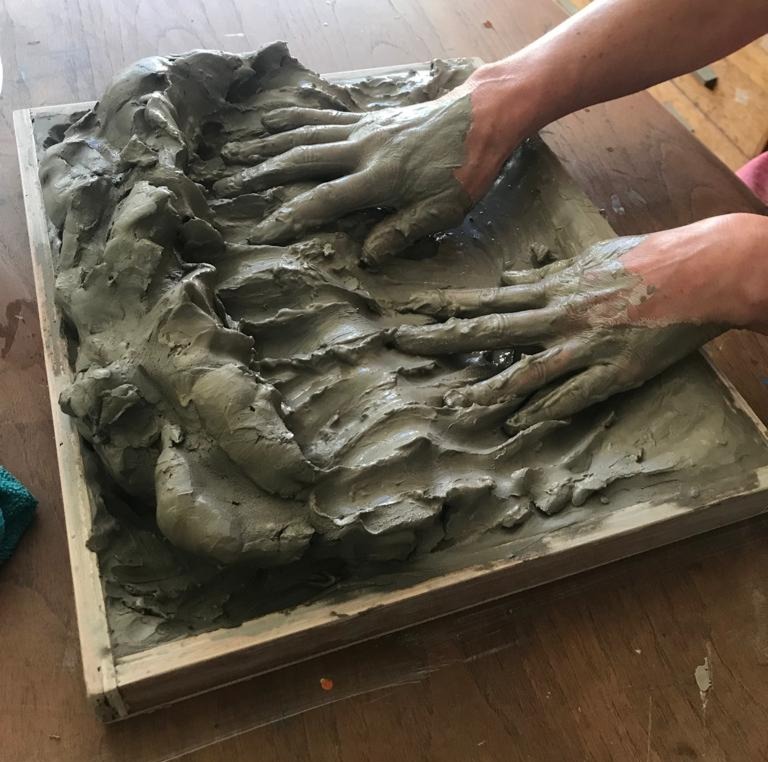 hands expressing emotion in a tray of clay