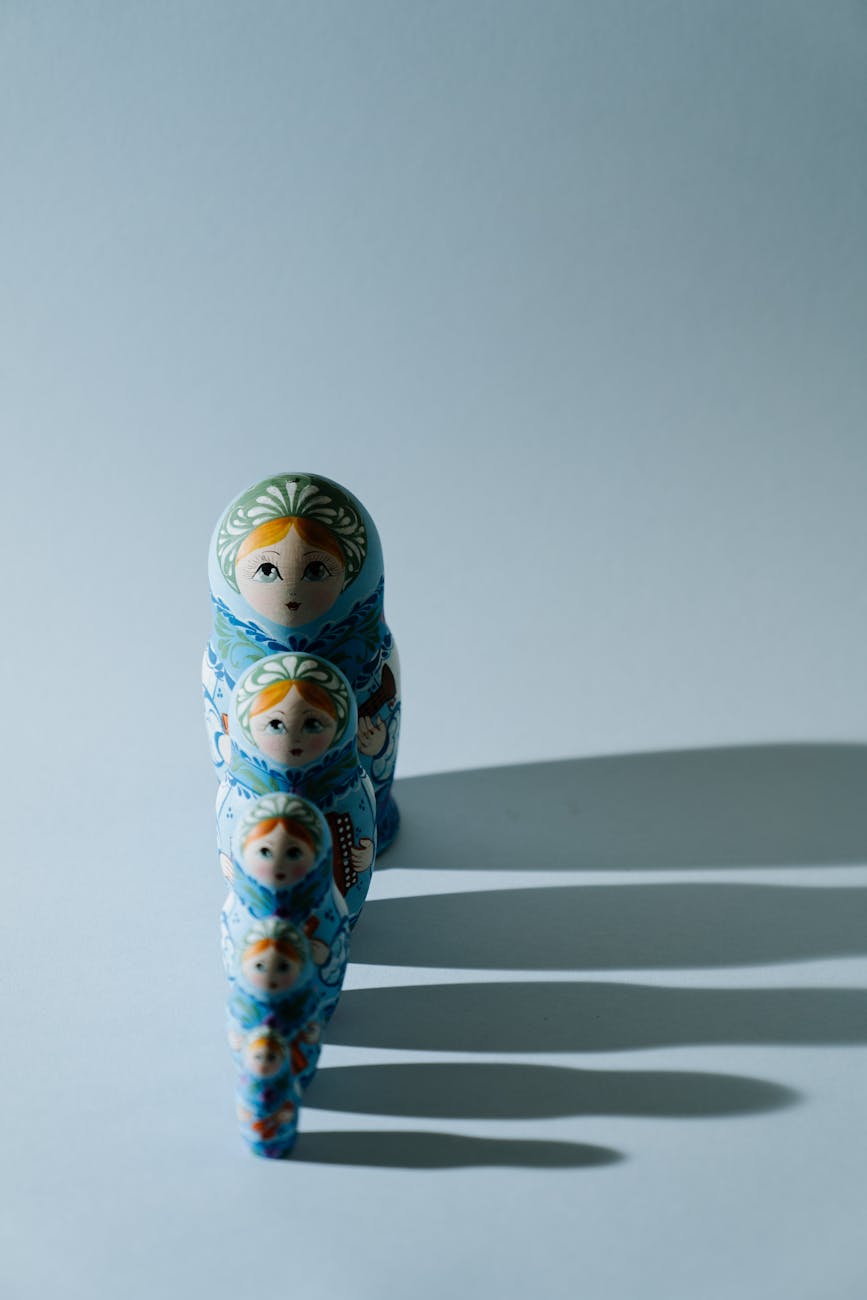 Russian dolls in a line with a shadow on one side, a metaphor for the emotional patterns we carry from childhood.