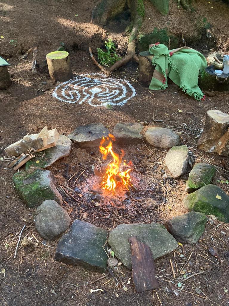 Women's circle in a wood with a fire in the centre - the location of the course